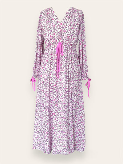 A long-sleeve, V-neck floral dress with a white background adorned with a delicate pink and purple floral pattern. The dress features a cinched waist with a pink drawstring tie, as well as matching pink ties at the sleeve cuffs.