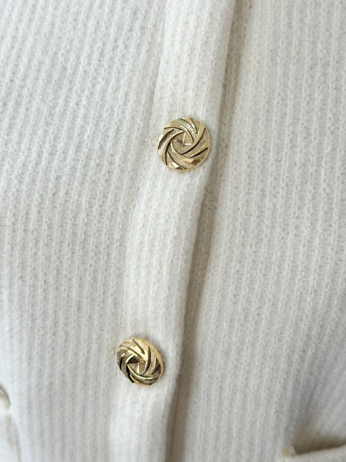 Close-up of a white textured fabric with gold buttons.
