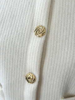 Close-up of a white textured fabric with gold buttons.
